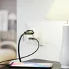 A white wall outlet with a white adapter plugged in, charging a smartphone and another device. Produktbild-Vorschau