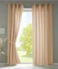 A window with beige curtains, one of which is tied back with a fabric tie. A small table with decorative items is visible to the left. Produktbild-Vorschau