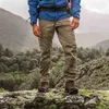 A person wearing hiking gear stands on a rocky outcrop overlooking a forest. Náhľad obrázku produktu