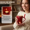 A woman is holding a red mug with a candle underneath, suggesting a cozy winter scene. Produktbild-Vorschau