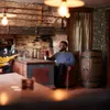 Two people are sitting at a table in a rustic-themed room, with one person holding a drink. Podgląd zdjęcia produktu
