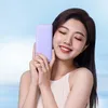 A young woman is holding a purple power bank to her cheek with her eyes closed and smiling. Produktbild-Vorschau