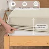 A hand is shown stretching a cream-colored fitted sheet over a mattress, indicating its size and material properties. Produktbild-Vorschau