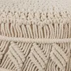 A close-up view of a cream-colored macrame pouf, showing the intricate woven texture and fringe details. Anteprima dell’immagine prodotto