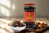 A jar of Laoganma chili oil with peanuts and a small bowl of the product are displayed on a wooden surface. Podgląd zdjęcia produktu