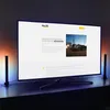 A large screen displaying a website with text and an image, flanked by two vertical LED lights. Produktbild-Vorschau