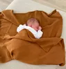 A newborn baby sleeping peacefully wrapped in a brown muslin blanket. Produktbild-Vorschau