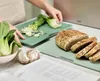 A person is preparing food in a kitchen, with ingredients and cutting boards on a counter. Anteprima dell’immagine prodotto