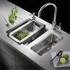 A modern kitchen sink setup with a faucet, a sink insert filled with herbs, and two glasses of drinks. Produktbild-Vorschau