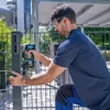A man is using a cordless impact wrench to attach a metal bracket to a fence post. Voir les images du produit