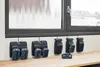 Several battery chargers and batteries are mounted on a wall above a wooden counter, with a window in the background. Produktbild-Vorschau