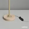 Close-up of the base of a lamp with a wooden accent and a black cord with a switch, on a gray surface. Produktbild-Vorschau