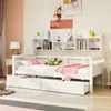 A white wooden daybed with drawers and a bookshelf headboard, decorated with pillows and a blanket. Voir les images du produit