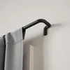 A close-up view of a black curtain rod with gray curtains hanging from it, mounted on a white wall. Podgląd zdjęcia produktu