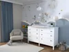 A nursery room with a changing table, armchair, and decorative wallpaper. Podgląd zdjęcia produktu
