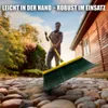 A person is sweeping a stone path in a garden setting. Produktbild-Vorschau