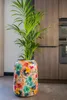 A tall, colorful floral patterned planter with a green plant inside, placed in a modern kitchen setting. Voir les images du produit