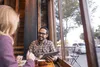 Two people are sitting at a table in a cafe, looking at a tablet. Voir les images du produit