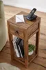A wooden side table with a drawer, holding a phone, notepad, books, and a small plant. Náhled obrázku produktu
