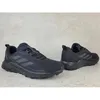 A pair of black Adidas Terrex outdoor hiking shoes are displayed on a concrete surface. Produktbild-Vorschau
