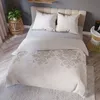 A neatly made bed with a beige damask duvet cover and two pillows. Podgląd zdjęcia produktu