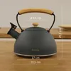 A gray kettle with a wooden handle is placed on a wooden surface, with measurement indicators shown. Náhľad obrázku produktu
