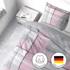 A neatly made bed with plaid bedding and a bedside table. Produktbild-Vorschau