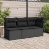 A black rattan sofa with cushions is placed on a paved patio, with a wooden fence and plants in the background. Produktbild-Vorschau