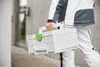 A person is carrying a white tool case with a green latch. Voir les images du produit