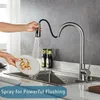 A person is washing a dirty plate under a kitchen faucet with a pull-down sprayer. Produktbild-Vorschau