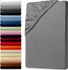 A fitted sheet is shown on a mattress, with a stack of fabric swatches in various colors to the left. Produktbild-Vorschau