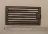 A cast iron grate is placed on a light gray surface next to a ruler. Náhled obrázku produktu