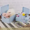 Several light blue wooden storage boxes are displayed on a rug, with toys and decorative items inside. Produktbild-Vorschau