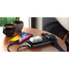 A Satechi Quatro Wireless Power Bank is shown charging an iPhone, AirPods, and an Apple Watch on a wooden table, next to a cup of coffee and a potted plant. Produktbild-Vorschau