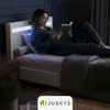 A woman is reading a book in bed, with LED lighting on the headboard. Produktbild-Vorschau