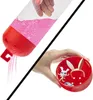 A collage showing two parts of a toy product. The top left shows a clear tube with pink glittery sand being poured out of a red cap. The bottom right shows a hand holding a red circular container with a small white character and bunny ears inside. Náhled obrázku produktu