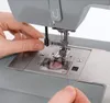 A close-up shot of hands threading a sewing machine. Náhled obrázku produktu