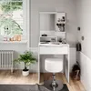 A white vanity table with a mirror and stool, set up in a room with a window and a plant. Podgląd zdjęcia produktu