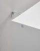 A close-up shot of a white shelf or cabinet being mounted to a wall with a metal bracket. Náhled obrázku produktu