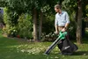 A man is using a leaf blower in a garden. Voir les images du produit