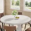 A round dining table with chairs in a well-lit room with windows overlooking a garden. Náhľad obrázku produktu