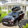 A dark red Mini Cooper car parked in front of a house, with a roof box and a bicycle attached. Produktbild-Vorschau