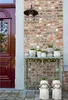 A decorative display of planters and a console table against a brick wall next to a red door. Voir les images du produit