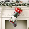 A Christmas stocking with a gnome decoration hanging from a fireplace mantel. Náhľad obrázku produktu