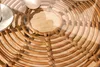 A close-up view of a rattan table with a glass top, showing the woven texture and a white cup on top. Produktbild-Vorschau