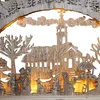 A wooden carved winter village scene with a church, snowmen, and a dog, illuminated by warm white LEDs. Náhľad obrázku produktu