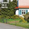 A wire mesh fence with a gate in front of a house and trees. Produktbild-Vorschau