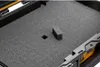 Close-up view of a foam insert inside a black case, with a small foam block and a square cutout visible. Produktbild-Vorschau