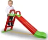 A child stands on the steps of a red and green slide. Náhled obrázku produktu