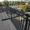 A balcony with a clothes drying rack attached to the railing, overlooking a street and a playground. Produktbild-Vorschau